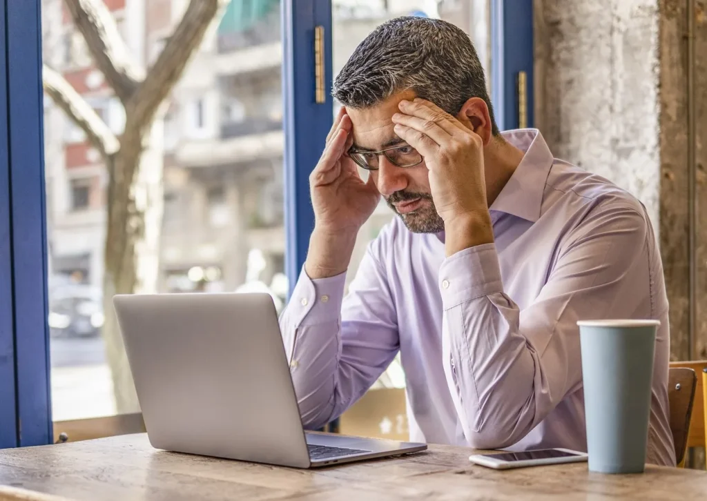 photo of a frustrated and overwhelmed small business owner reviewing his financial statements, struggling to get ahead and stay organized